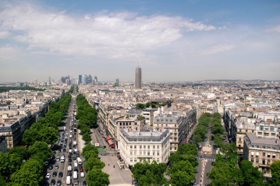 An aerial view of a city skyline with tree-lined boulevards and traffic below