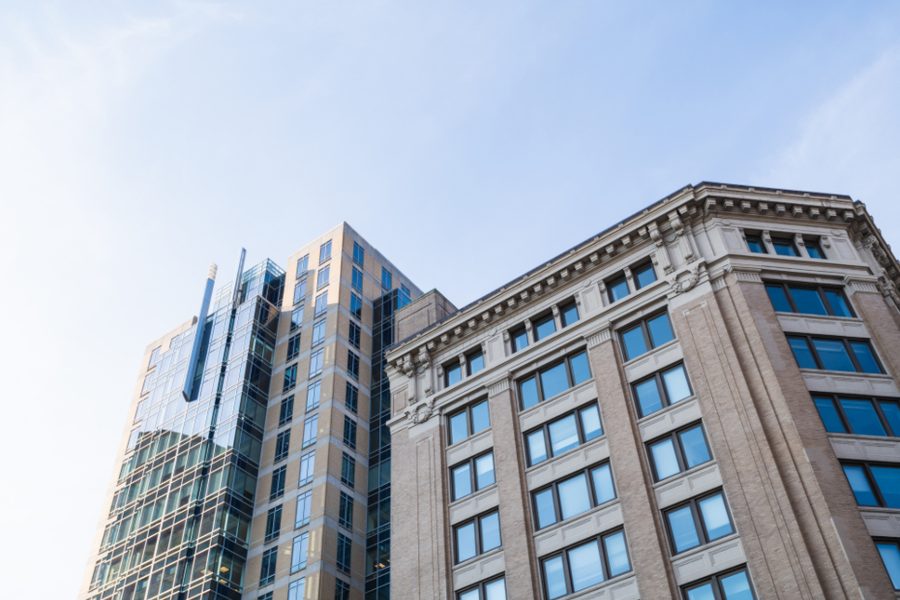 The upper floors of glass and stone office buildings against a blue sky